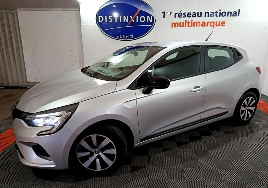 Vue 3/4 avant droit d'une Renault Clio gris clair avec feux LED allumés et jantes spécifiques en concession.