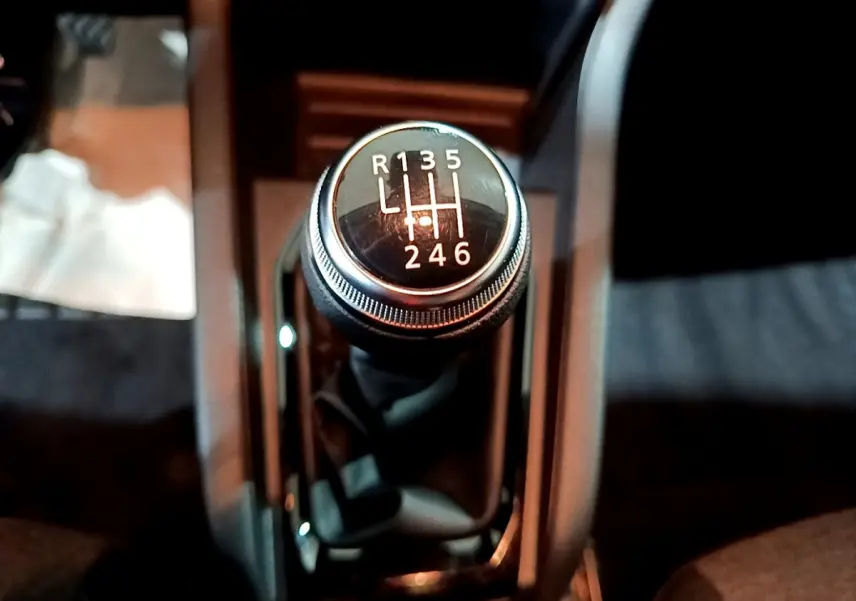 Le levier de vitesses manuel noir de la Renault Clio gris clair, vue en gros plan depuis l'intérieur central.