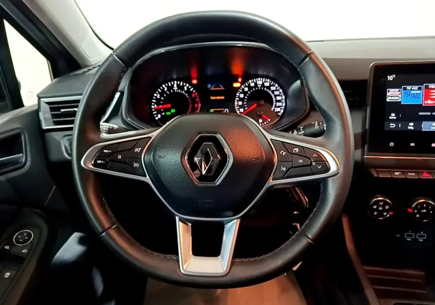 Vue intérieure centrée sur le volant cuir noir de la Renault Clio 2023 avec tableau de bord et écran tactile visible à droite.