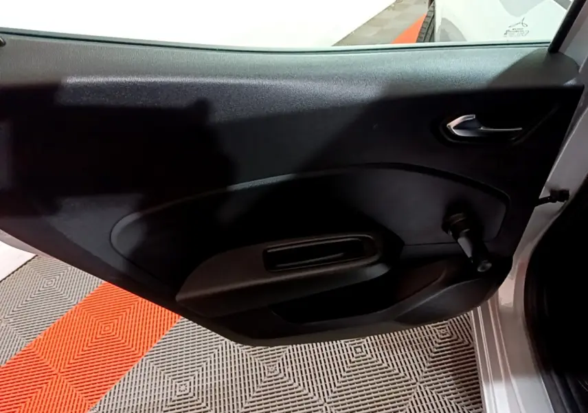 Vue intérieure sur la porte arrière droite noire de la Renault Clio gris clair avec poignée de fenêtre manuelle.