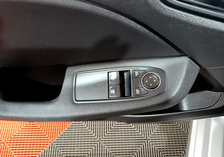 Gros plan sur la commande des vitres et rétroviseurs côté gauche d'une Renault Clio gris clair 2023.