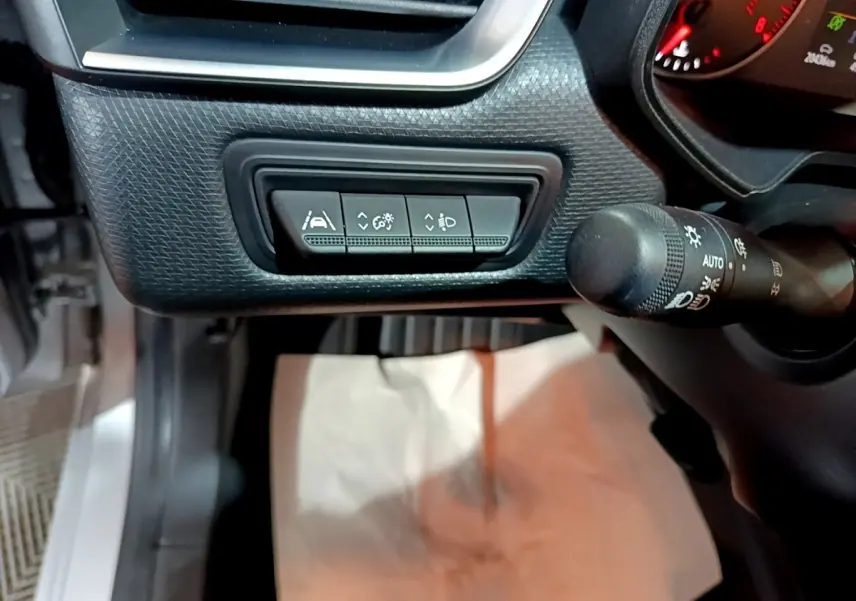 Vue intérieure côté gauche du tableau de bord gris clair de la Renault Clio 2023 avec commandes d'assistance et manette d'éclairage.