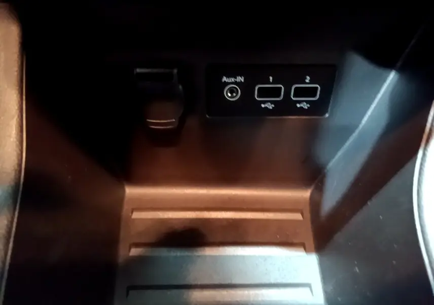Gros plan sur la prise USB et port Aux-in dans le rangement central noir de la Renault Clio gris clair 2023.