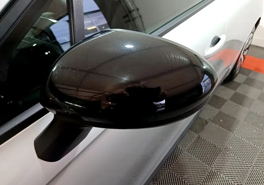 Gros plan sur le rétroviseur noir côté gauche d’une Renault Clio gris clair vue de profil.