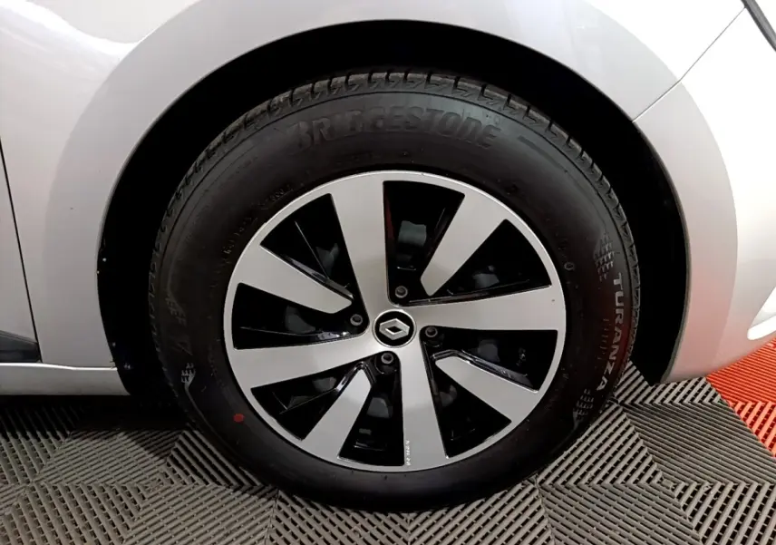 Gros plan sur la roue avant droite gris clair de la Renault Clio 2023 avec jante noire et argentée au design moderne.