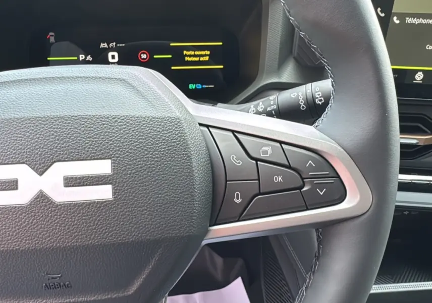 Gros plan sur le volant cuir noir du Dacia Bigster Hybrid 155 Extreme Plus avec commandes multifonctions et tableau de bord digital.