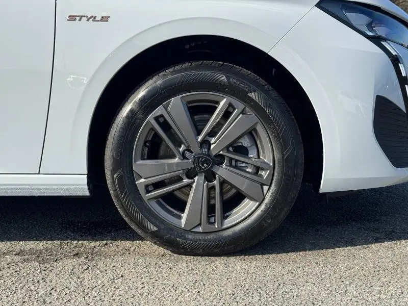 Gros plan sur la roue avant droite et l’aile blanche Okénite d’une Peugeot 308 Style avec jante alu et logo Peugeot.