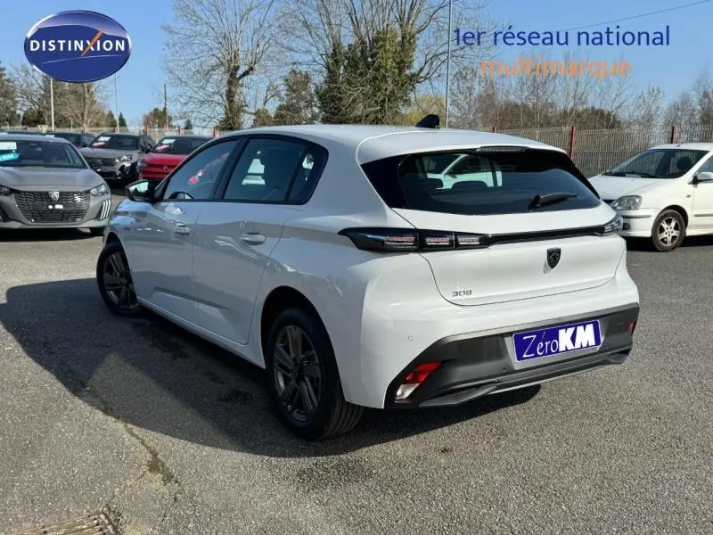 Vue 3/4 arrière droite d'une Peugeot 308 blanche Okénite avec feux arrière LED et jantes alu sombres.