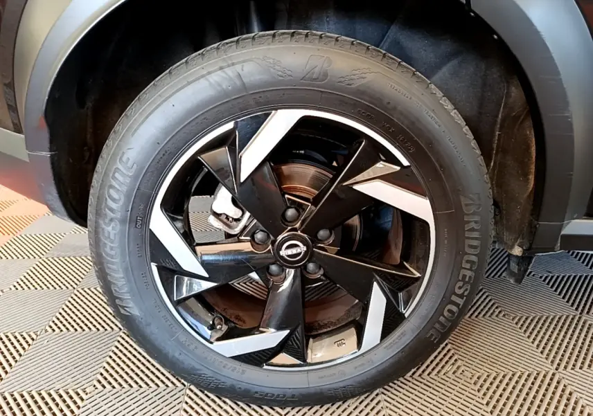 Gros plan sur la roue avant droite noire du Nissan Juke 2022 avec jante alliage noire et détails argentés.