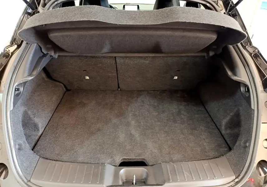 Coffre ouvert vu de l'arrière d'un Nissan Juke noir 2022, montrant l'espace de chargement vide et la tablette de coffre relevée.