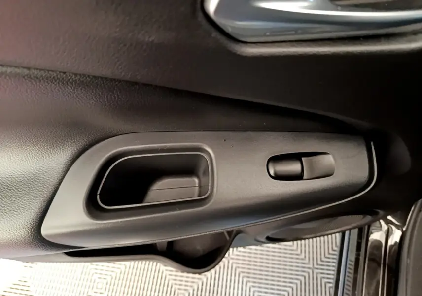 Poignée intérieure de porte côté conducteur en plastique noir sur Nissan Juke DIG-T 114 DCT noir, vue rapprochée.