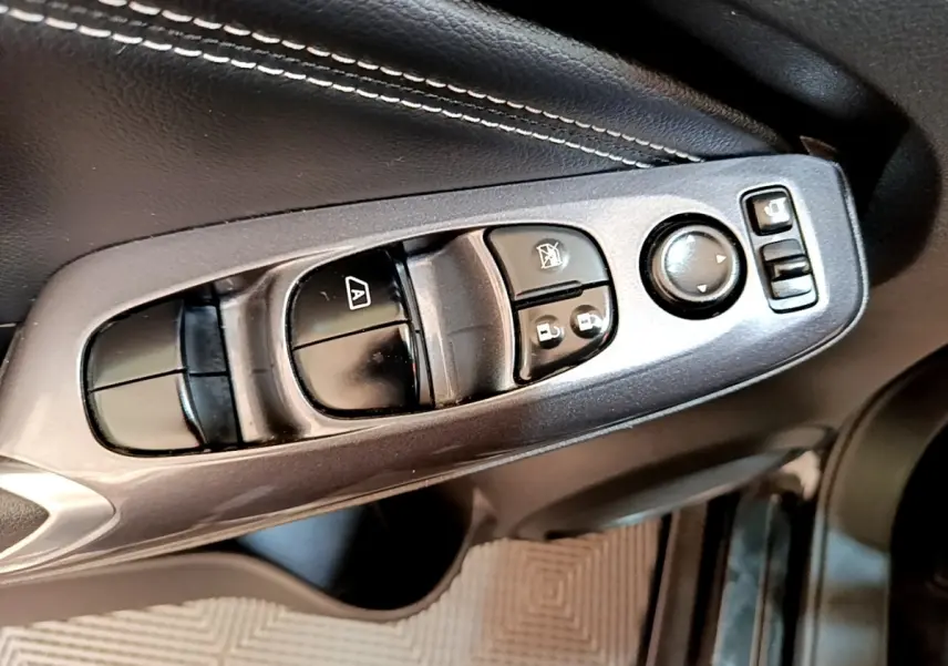 Gros plan sur la commande des vitres et rétroviseurs côté conducteur du Nissan Juke noir 2022.