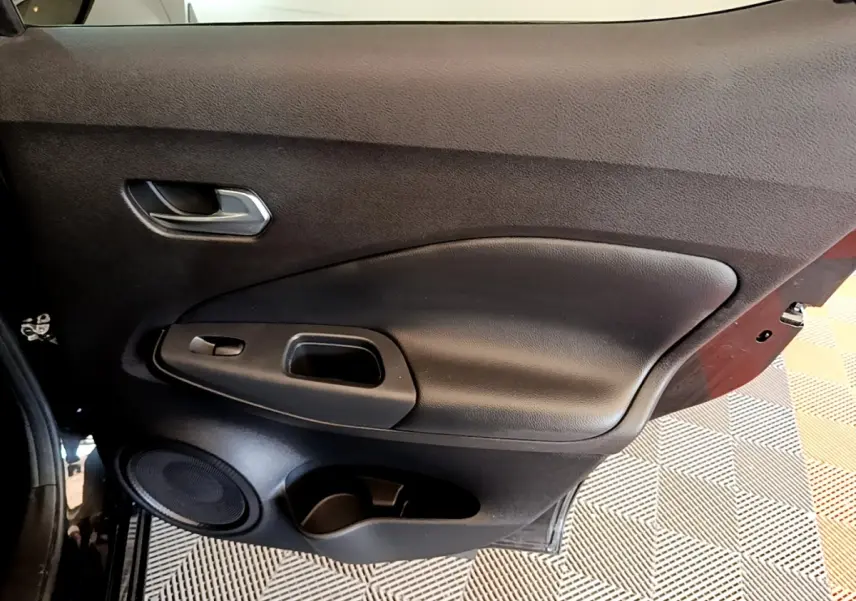 Vue intérieure côté gauche de la porte noire du Nissan Juke 2022 avec poignée, haut-parleur et rangement intégré.
