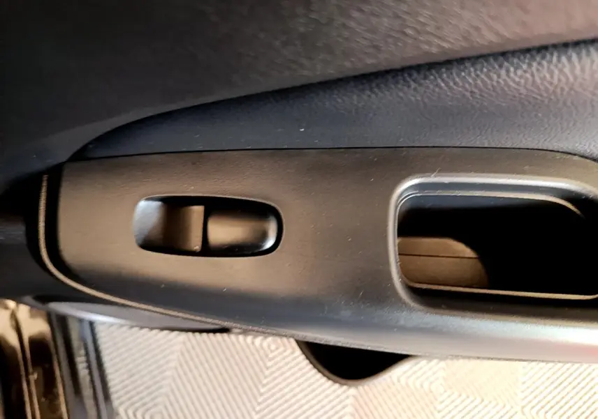 Détail de la poignée intérieure noire de porte côté conducteur du Nissan Juke DIG-T 114 DCT 2022.