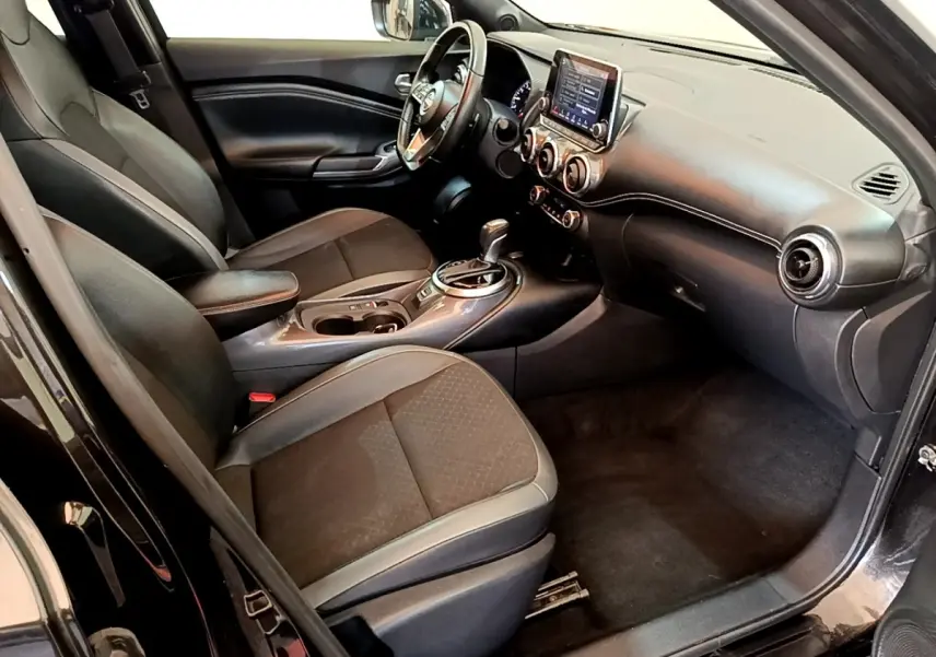 Vue intérieure côté conducteur du Nissan Juke noir 2022, avec tableau de bord moderne et écran tactile central.