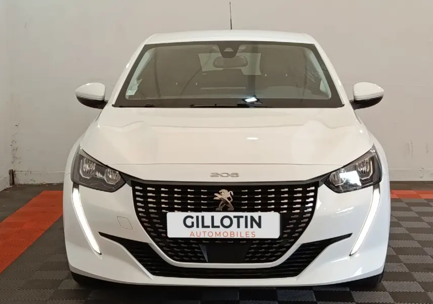 Peugeot 208 blanc vue de face avec calandre noire et feux LED en forme de griffes allumés.