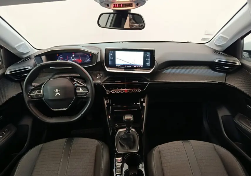 Vue intérieure frontale du tableau de bord noir et volant cuir de la Peugeot 208 PureTech 100 S&S Allure Business 2021.