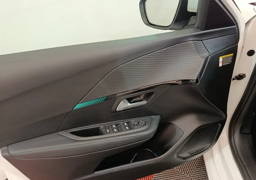 Vue rapprochée de la porte avant gauche blanche d'une Peugeot 208 2021 avec garniture noire et commandes électriques.