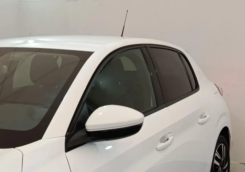 Vue latérale droite d'une Peugeot 208 blanche avec rétroviseur et poignées assortis, vitres teintées.