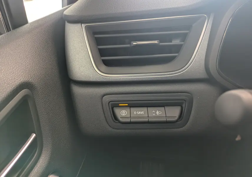 Détail des commandes E-SAVE et réglage des phares sous la sortie d'air côté gauche dans l'habitacle du Renault Captur hybride 2025.