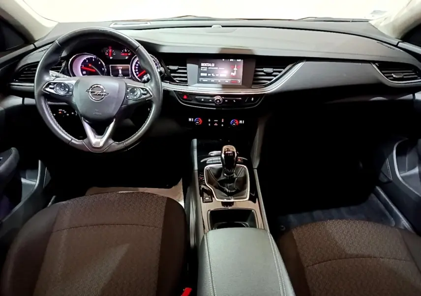 Vue intérieure avant de l'Opel Insignia 2019, tableau de bord noir avec écran tactile et volant cuir multifonctions.