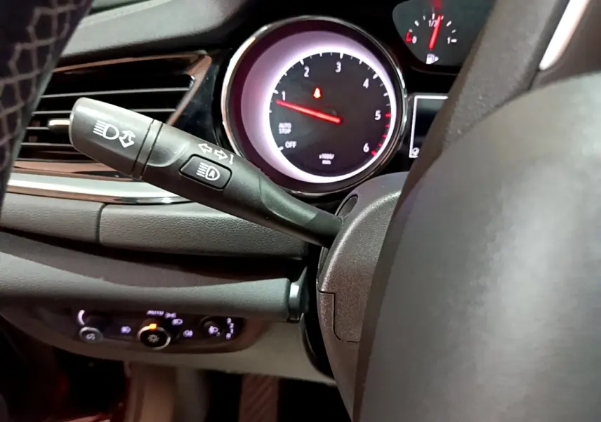 Vue rapprochée du commodo gauche et du compte-tours éclairé de l’Opel Insignia 1.6 Diesel rouge, tableau de bord sombre.