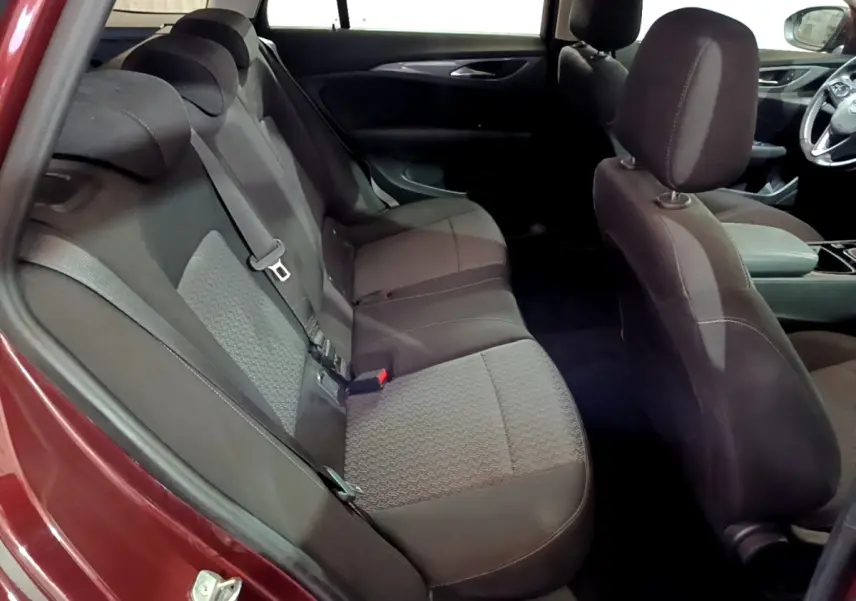 Vue intérieure côté gauche sur la banquette arrière noire de l'Opel Insignia rouge, avec sièges tissu et ceintures visibles.