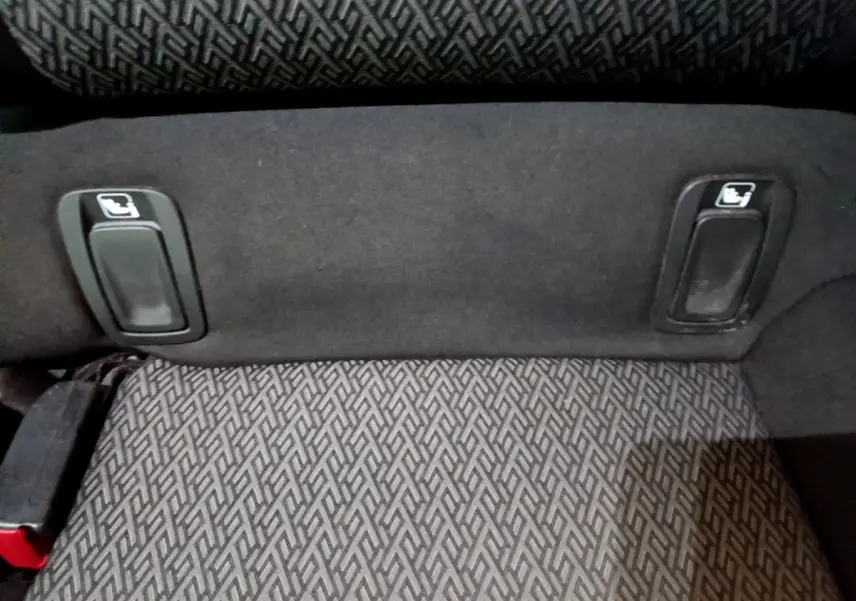 Détail des commandes de rabattement des sièges arrière sur la banquette tissu gris foncé de l'Opel Insignia.