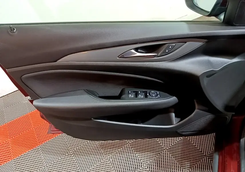 Vue côté gauche de la porte intérieure noire de l’Opel Insignia rouge, avec commandes des vitres et rétroviseur.