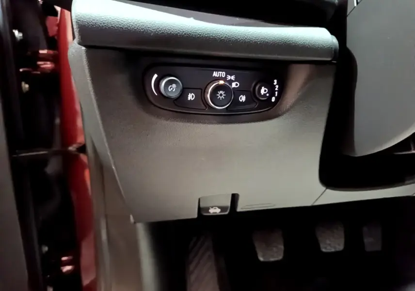 Vue rapprochée du panneau de commandes d’éclairage côté gauche dans l’habitacle d’une Opel Insignia rouge.