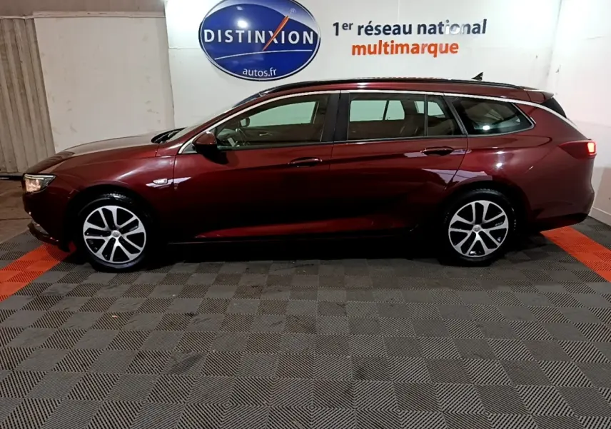 Opel Insignia break rouge vue de profil côté gauche, stationnée en intérieur sur sol damier.