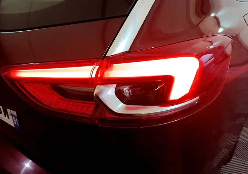 Gros plan sur le feu arrière droit rouge allumé d’une Opel Insignia rouge, vue arrière en faible luminosité.
