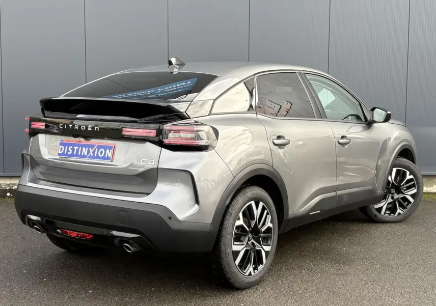 Vue 3/4 arrière droite d'une Citroën C4 Hybrid gris Mercury avec jantes alliage et toit noir brillant.