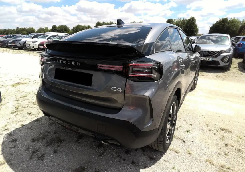 Vue 3/4 arrière droite d'une Citroën C4 Hybrid 145 gris Mercury avec feux arrière LED et toit noir brillant.