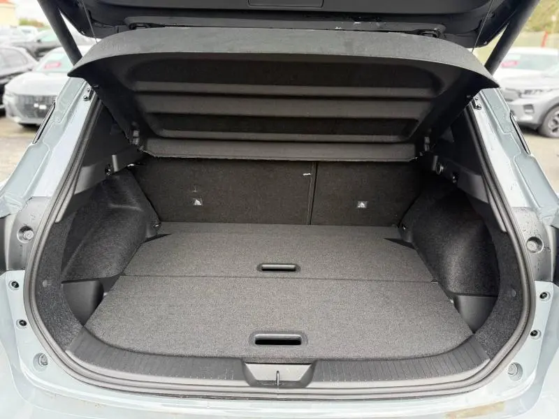 Coffre ouvert vu de l'arrière du Nissan Qashqai Hybrid e-POWER 2025 en Gris Argile, montrant un espace de chargement plat et spacieux.