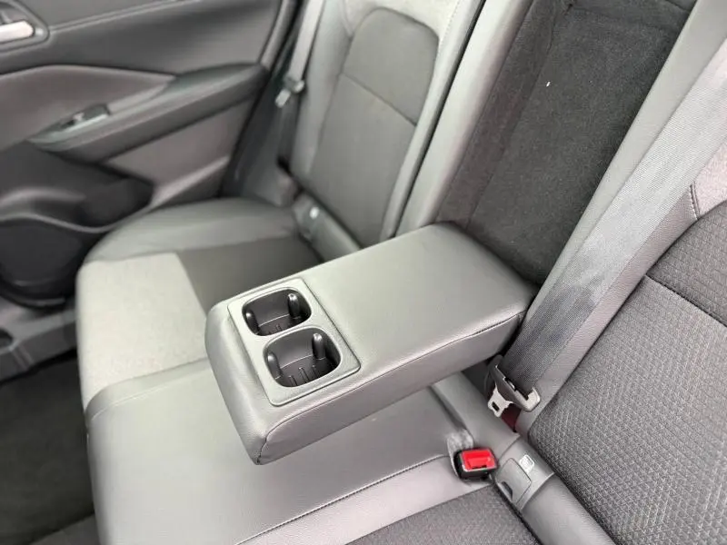 Vue intérieure sur l'accoudoir central arrière avec porte-gobelets du Nissan Qashqai Hybrid e-POWER 2025 en tissu gris.