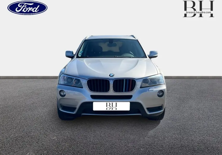 Vue avant d'un BMW X3 Mineralsilber 2013 avec calandre noire et phares halogènes allumés.