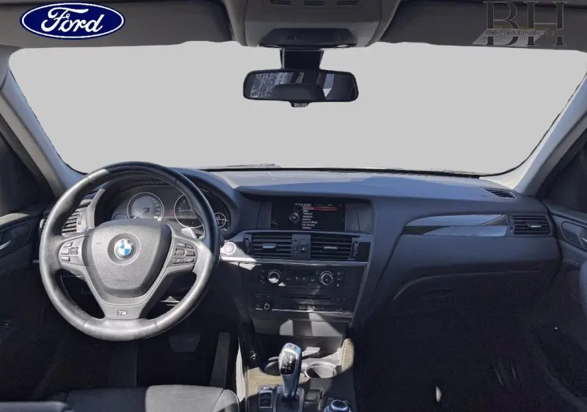 Intérieur BMW X3 2013 vu de face, tableau de bord noir avec volant cuir et levier de vitesse automatique.