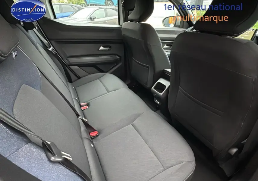 Vue intérieure arrière côté gauche du Dacia Duster 2025 blanc arctic, montrant la banquette et les sièges avant noirs.