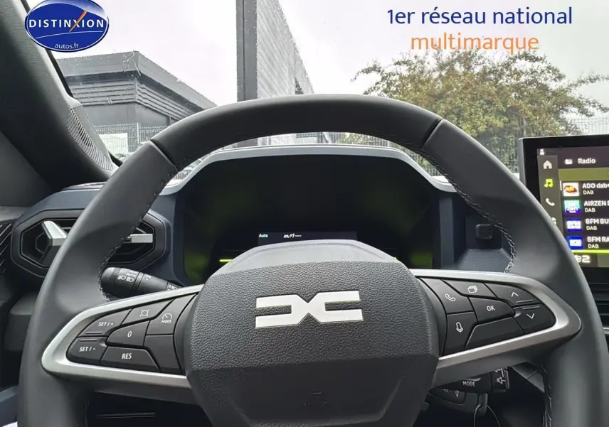 Vue intérieure centrée sur le volant multifonction noir du Dacia Duster 2025 avec tableau de bord et écran tactile visibles.