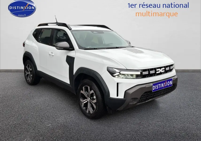 SUV Dacia Duster blanc arctic en 3/4 avant droit avec jantes alu et barres de toit noires visibles.