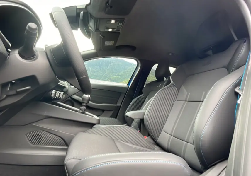 Intérieur avant de la Renault Clio V E-Tech 145 Esprit Alpine 2025, sièges noirs avec surpiqûres bleues et volant visible.