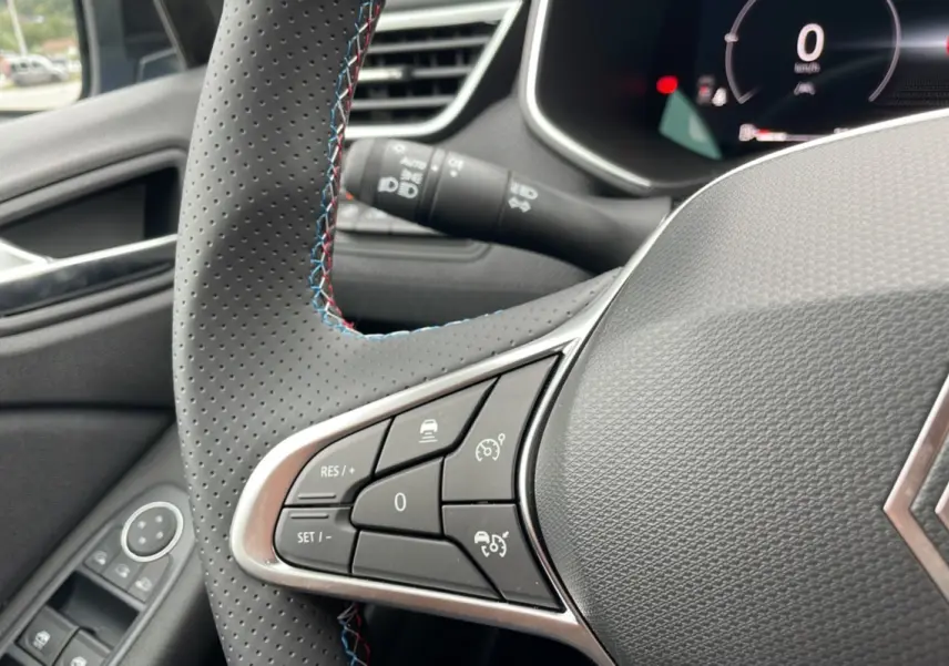 Gros plan sur le volant perforé de la Renault Clio V E-Tech 145 Esprit Alpine 2025 avec surpiqûres tricolores.