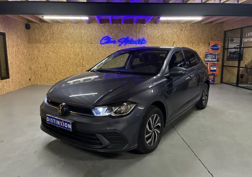 Volkswagen Polo gris en 3/4 avant droit dans un showroom avec éclairage bleu et jantes bi-ton.