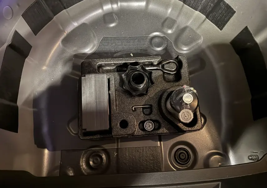 Gros plan sur le coffre à outils gris métallique du Volkswagen Polo VI 1.0 TSI 95 Edition 50, montrant l’emplacement de la roue de secours.