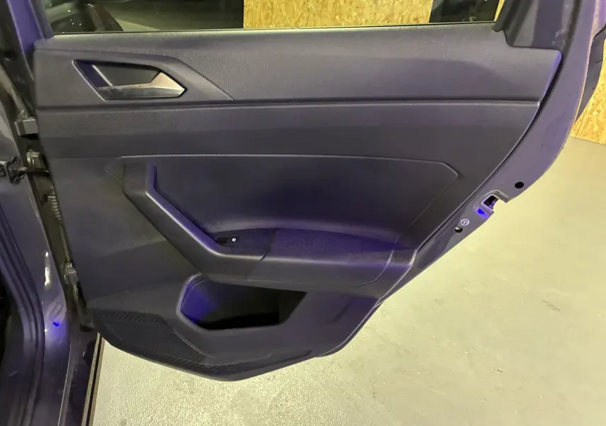 Porte arrière gauche ouverte d'une Volkswagen Polo gris 2025, montrant la garniture intérieure noire et la poignée intégrée.