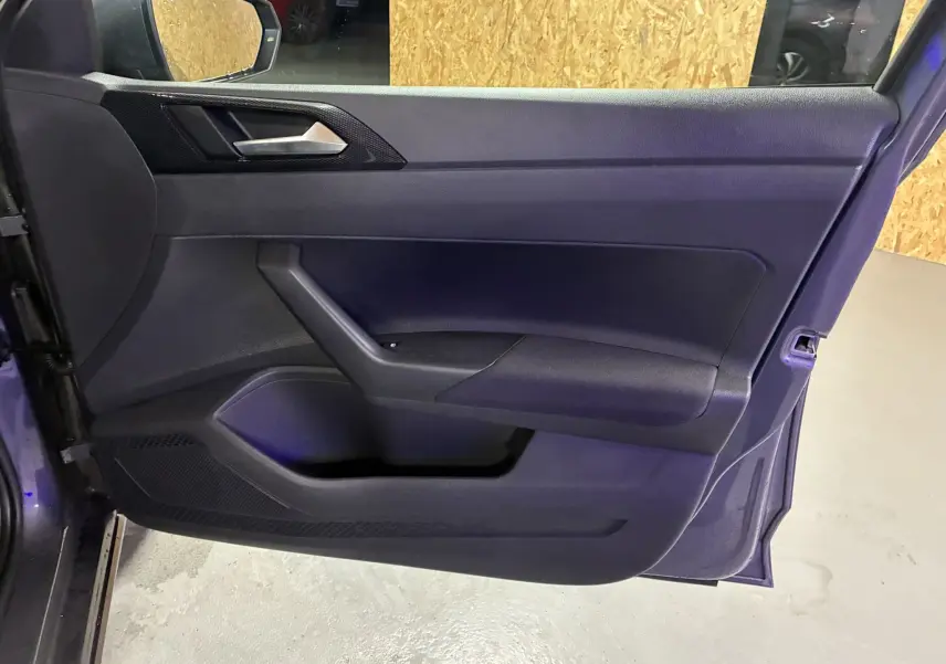 Vue intérieure de la porte côté gauche d'une Volkswagen Polo gris 2025, avec poignée argentée et garniture noire.