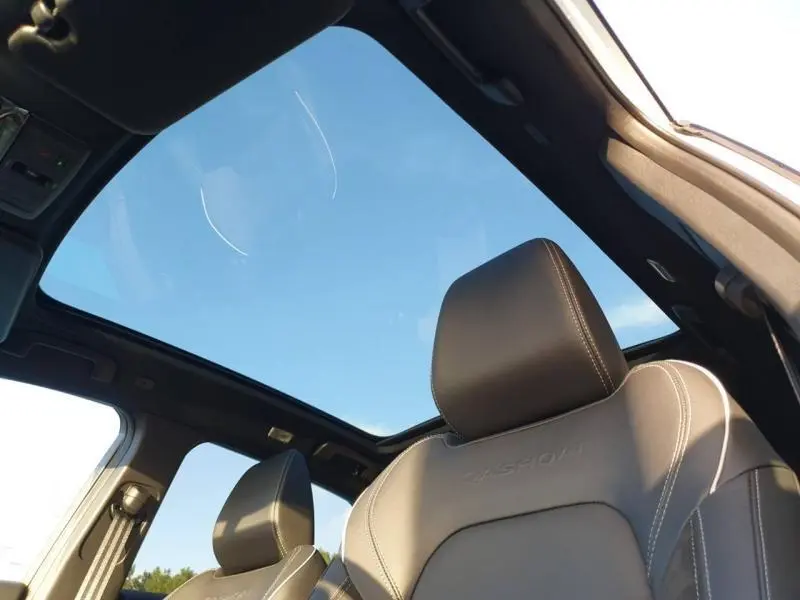 Vue intérieure du Nissan Qashqai 2025 Hybrid e-POWER avec toit panoramique et sièges en cuir brun foncé brodés Qashqai.