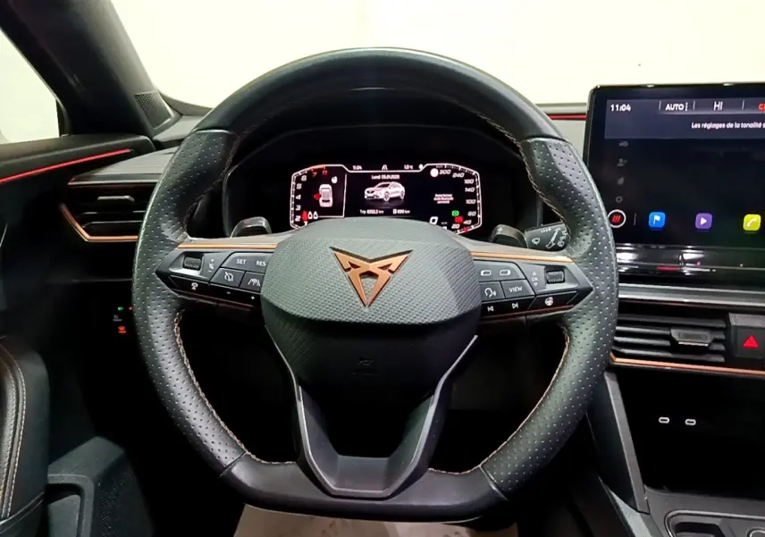 Vue intérieure centrée sur le volant cuir et alu perforé de la CUPRA Formentor 2024 avec tableau de bord digital et écran tactile.