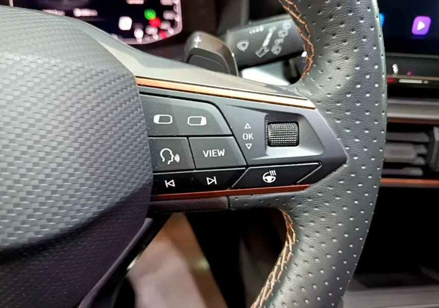 Gros plan sur le volant cuir perforé gris foncé de la CUPRA Formentor 2024 avec commandes multifonctions et finition alu.